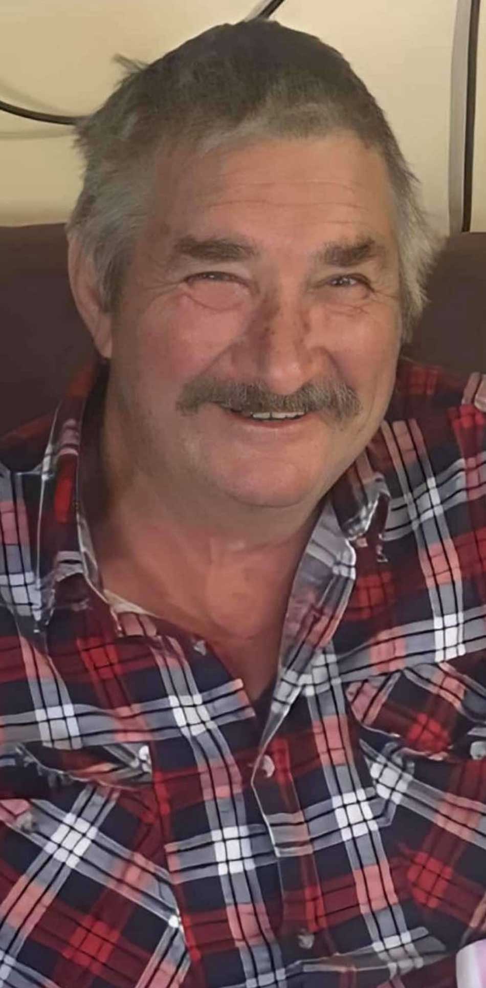A man with a mustache wearing a plaid shirt.
